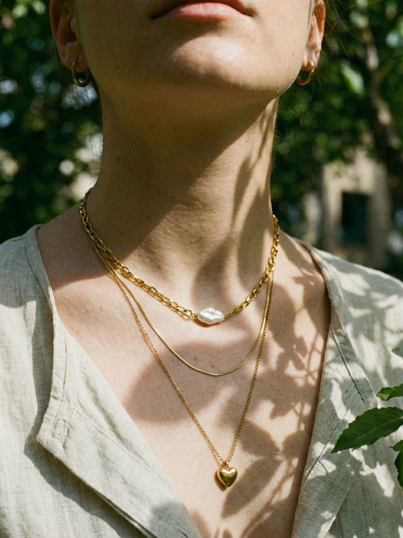 3er-Kette Herzstueck Lifestyle Foto warmes Licht – dreireihige Goldkette mit Herzanhaenger elegant getragen