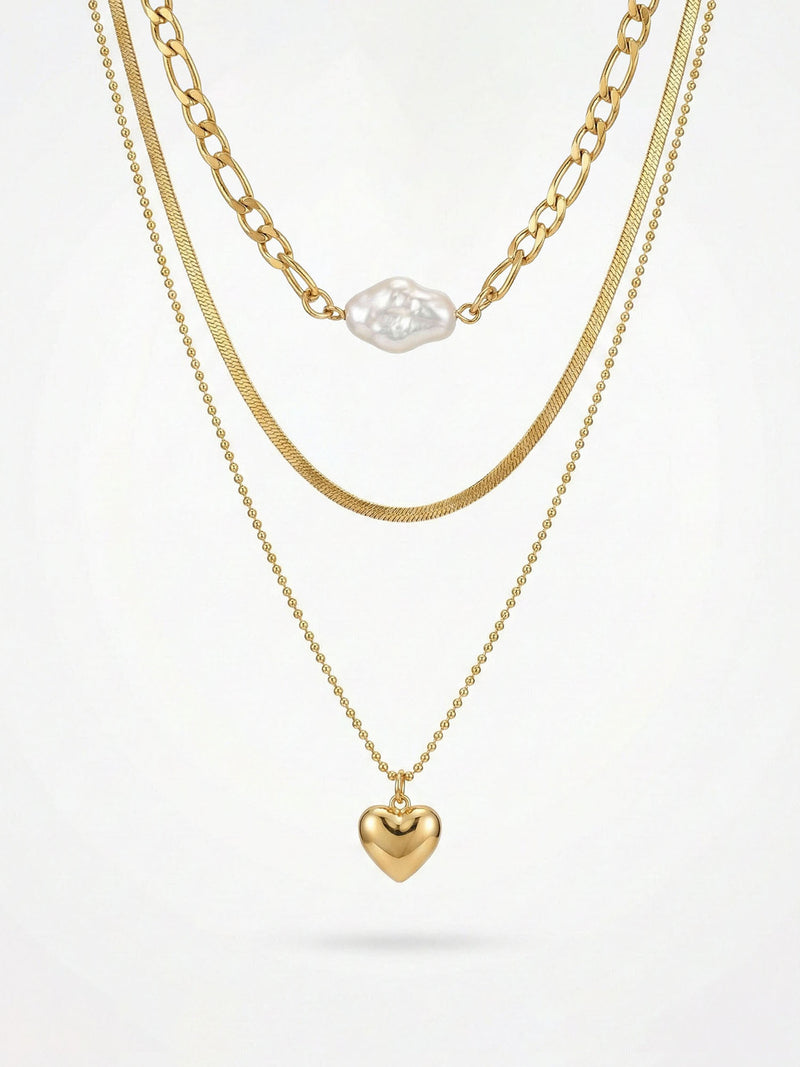 3-teilige goldene Halskette mit Herzanhänger - Vergoldete Layering-Kette mit weißer Perle und goldenem Herz auf weißem Hintergrund