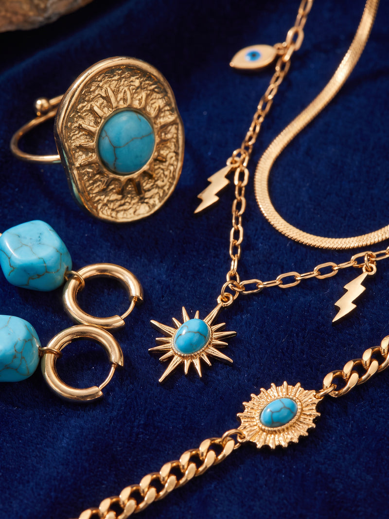 Nahaufnahme des türkisfarbenen Schmucks und seiner goldfarbenen Details – Anima in Fiore