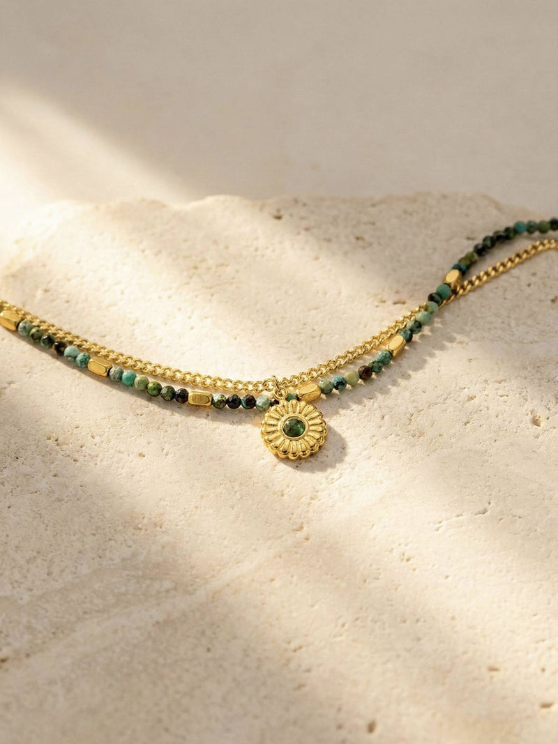 Afrikanischer Turkis Perlenarmband auf hellem Steinuntergrund - Zweireihiges Boho Armband mit Goldkette im Sonnenlicht