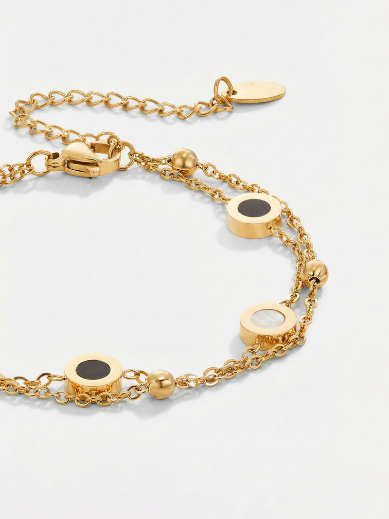 Luna Dual Armband Detailaufnahme mit weichem Licht - schwarz-weisse Emaille-Kreise auf Goldkette