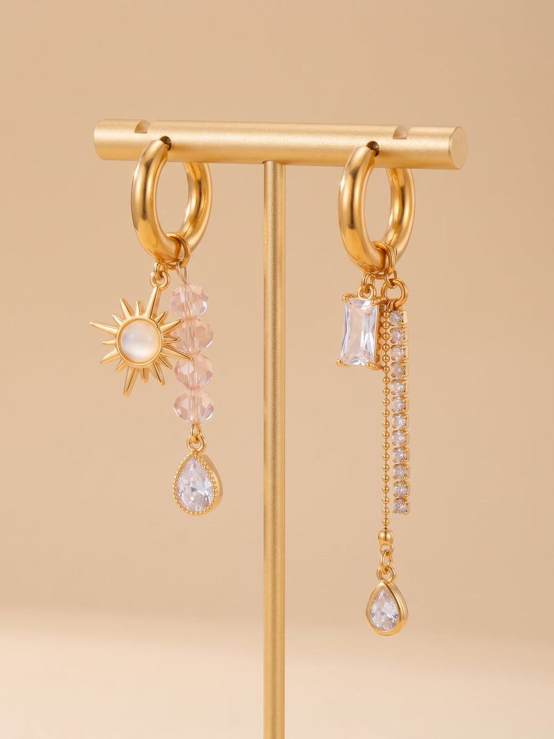 EH05C: Asymmetrische goldfarbene Creolen mit Sonne, rosa Perlen und klaren Tropfen am Schmuckständer.