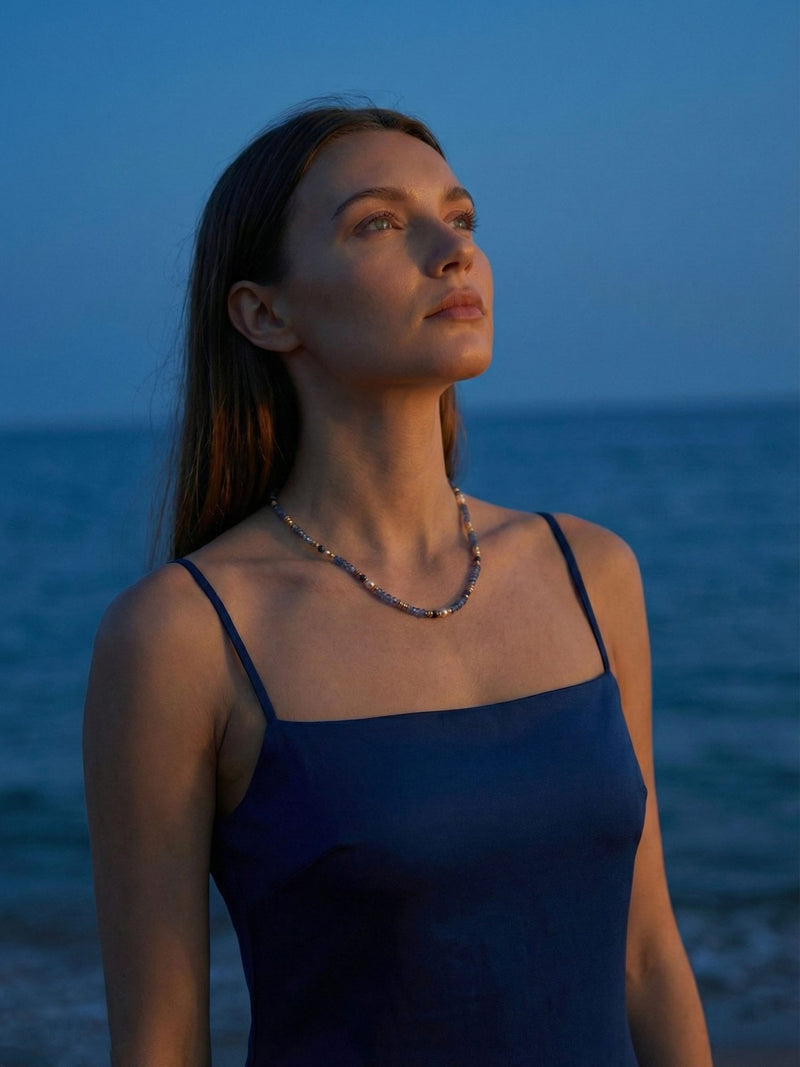 Sodalith Perlenkette Ocean Night kuenstlerisches Portrait - Model blickt zum Himmel am Meer bei Daemmerung