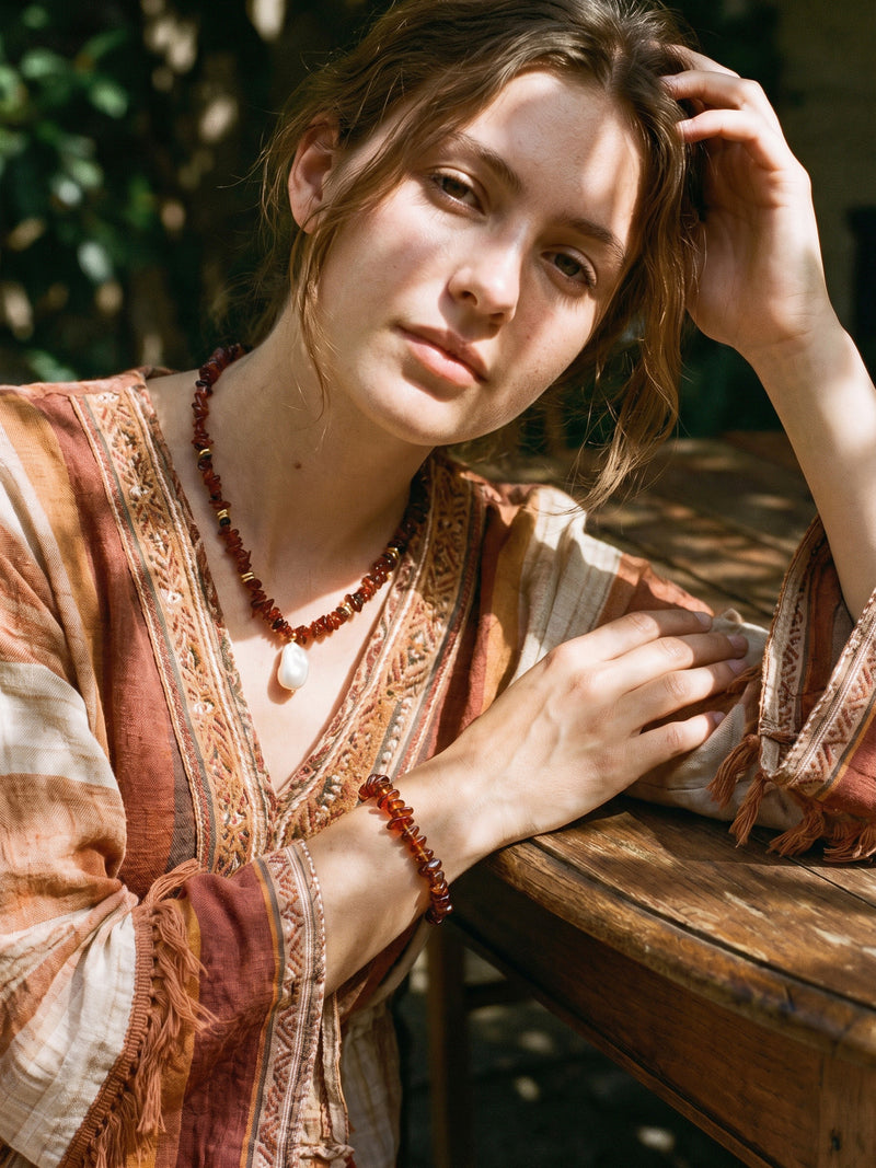 Volcano Blossom necklace and bracelet together on model, casually worn at a wooden table
