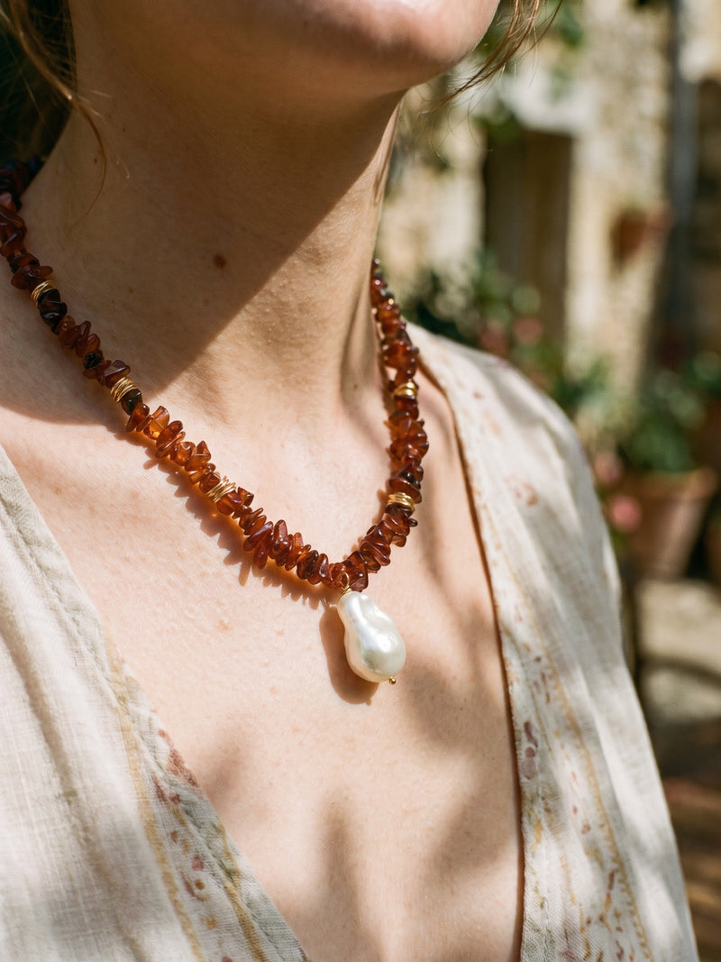 Vulkanblüte necklace with reddish-brown chips and white pearl, close-up on neck