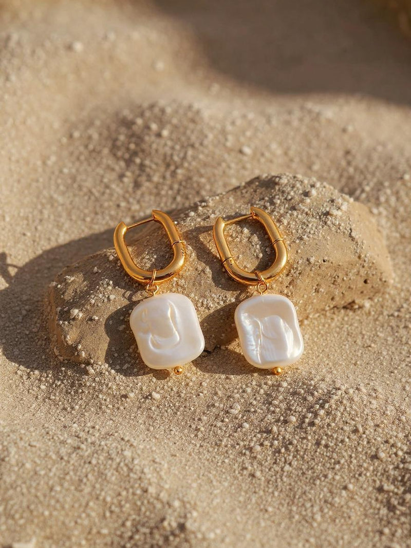 Marea Ohrringe Detailansicht – goldene Perlenohrringe auf Sand mit maritimem Flair