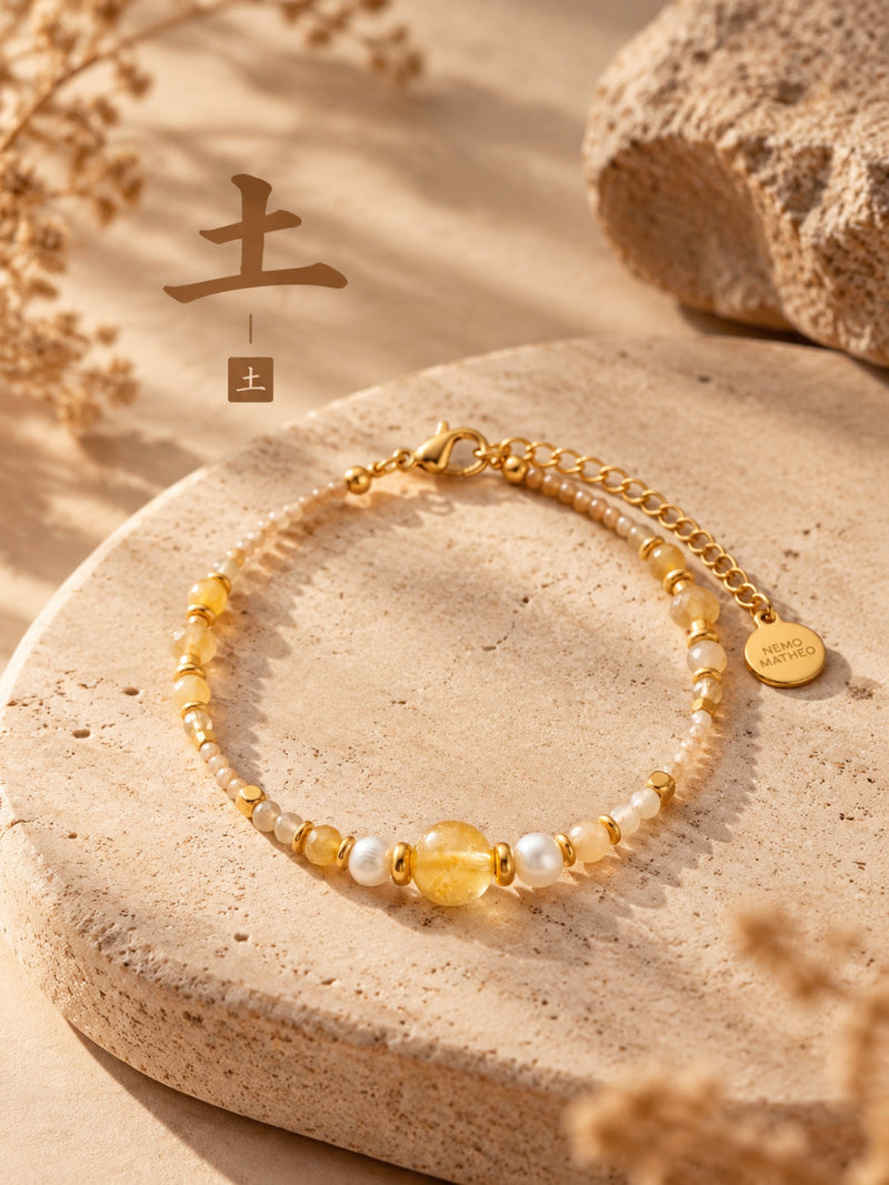 SL63D: Armband Cinque Elementi Erde mit gelben Perlen, als Stillleben mit dem chinesischen Elementzeichen.