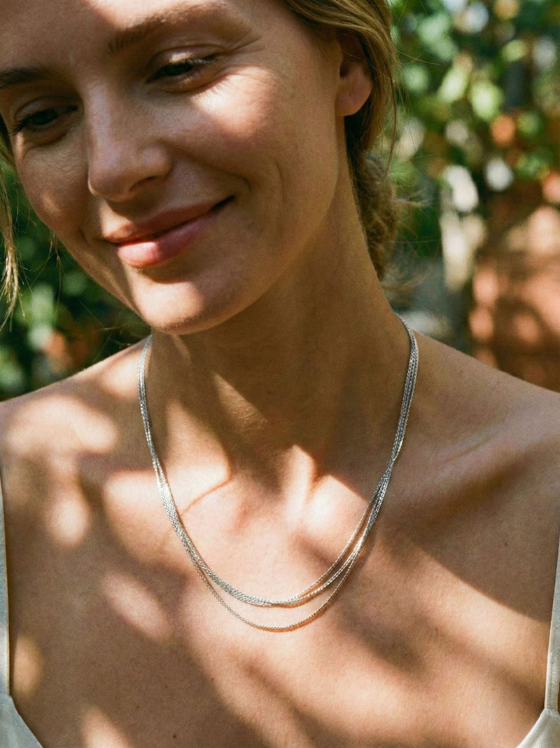 Triple Layer Silber Kette getragen – Model traegt elegante silberne Mehrfachkette