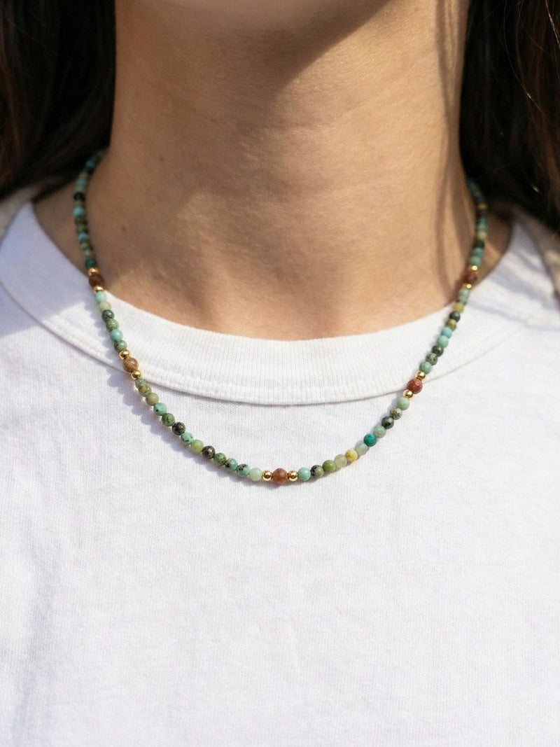 Kette Tuerkis Goldsand – Detailaufnahme am Hals getragen, Nahaufnahme Anhaenger und Perlen