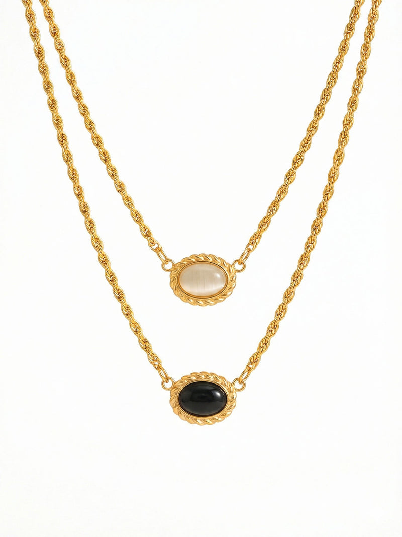 Yin Yang Glow Kette Produktfoto – vergoldete Doppelkette mit hellem und dunklem Katzenauge-Stein auf weissem Hintergrund