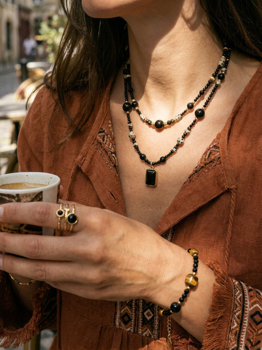 Shop the Look in Schwarz und Gold: Kette Eclipse, Kette Monolith, Armband Eclipse und Ring Obsidiana. Das unten verlinkte Dreier-Set enthält beide Ketten und das Armband; der Ring ist zusätzlich erhältlich.