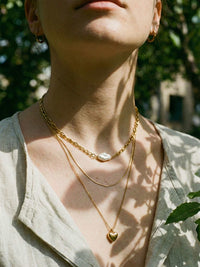 3er-Kette Herzstueck Lifestyle Foto warmes Licht – dreireihige Goldkette mit Herzanhaenger elegant getragen