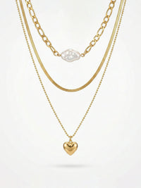 3-teilige goldene Halskette mit Herzanhänger - Vergoldete Layering-Kette mit weißer Perle und goldenem Herz auf weißem Hintergrund