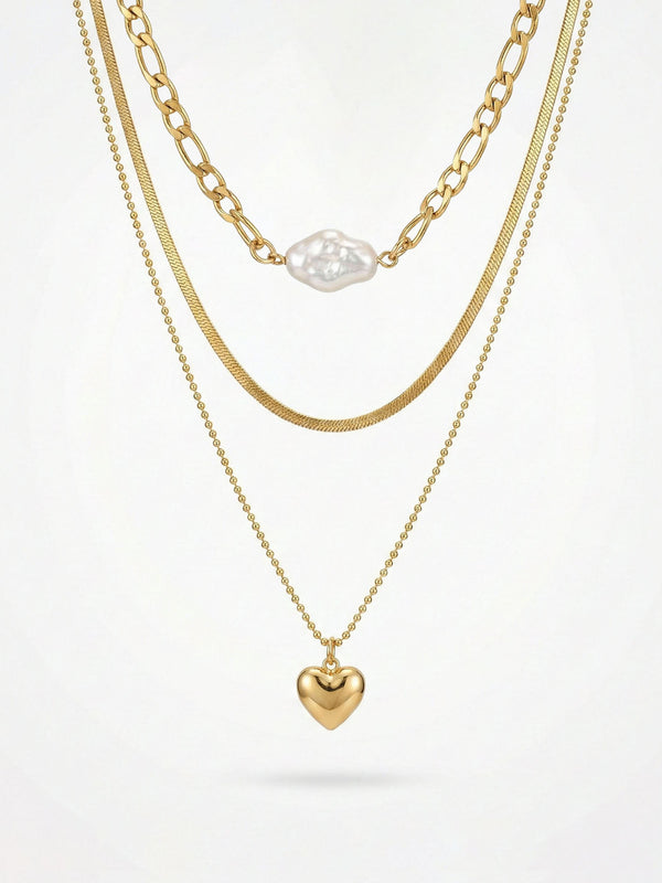 3-teilige goldene Halskette mit Herzanhänger - Vergoldete Layering-Kette mit weißer Perle und goldenem Herz auf weißem Hintergrund