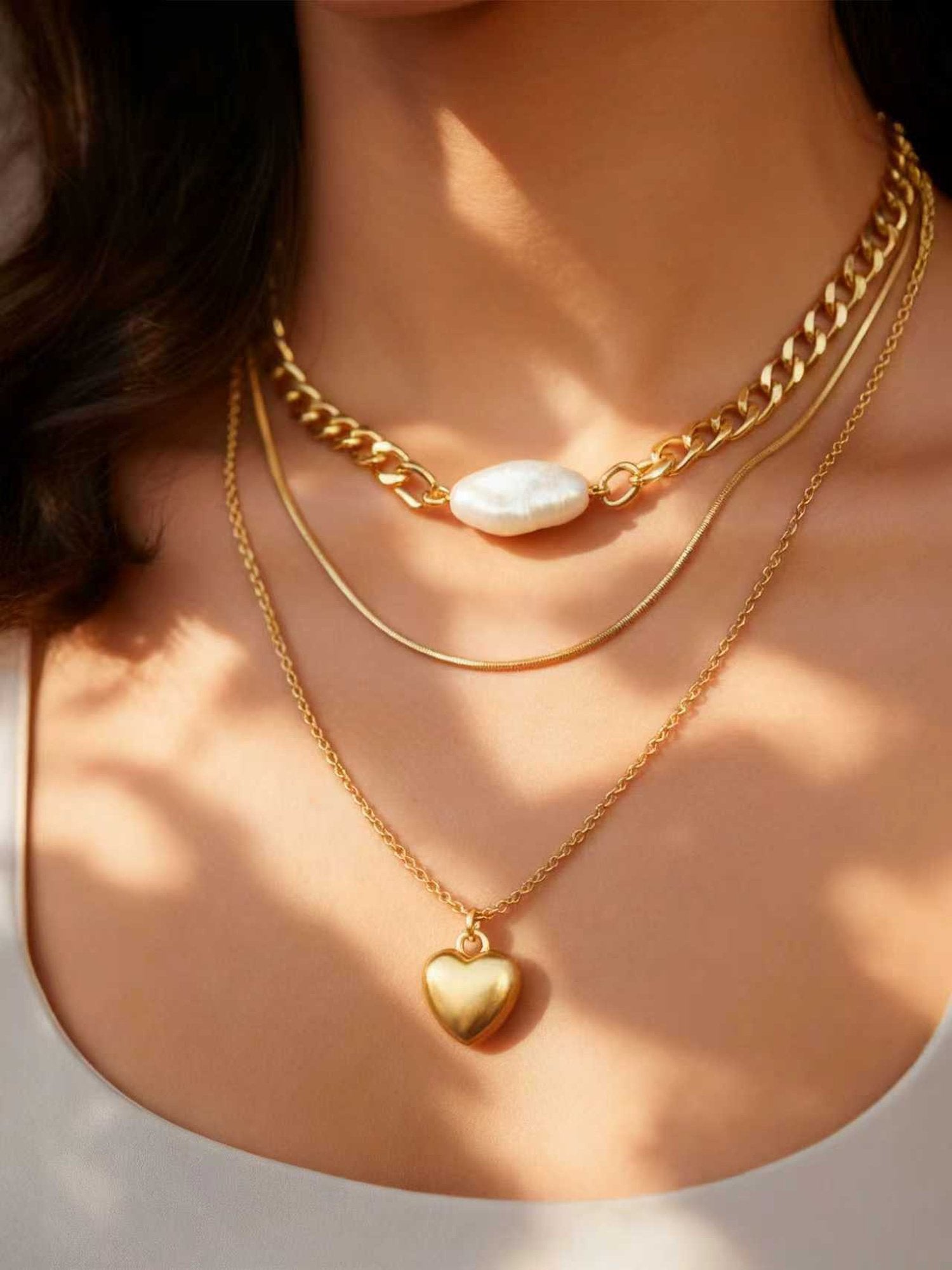 Elegante dreireihige Halskette mit Herzanhänger in 18K vergoldet - Goldene Layering-Kette mit Perle und Herz-Charm getragen am Hals