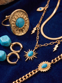 Nahaufnahme des türkisfarbenen Schmucks und seiner goldfarbenen Details – Anima in Fiore