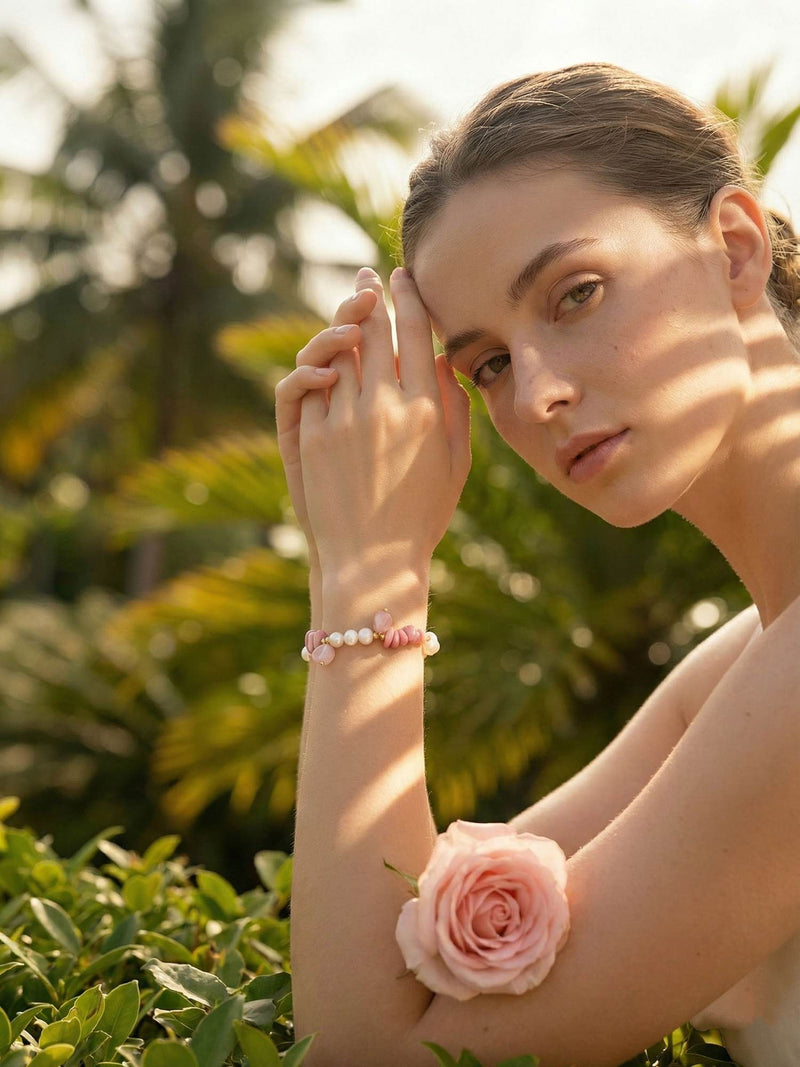 Junge Frau trägt Rosengarten Armband im tropischen Garten mit Rose - Natürlicher Boho Lifestyle Schmuck