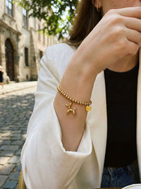 Armband Glueckshund am Handgelenk getragen – goldene Perlen und verspielter Ballonhund-Charm am Arm