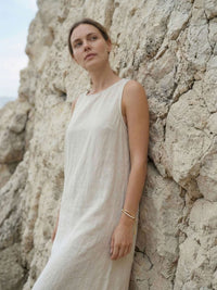 Model trägt Perlenarmband Elva im Leinenkleid vor mediterraner Felsenlandschaft