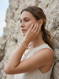 Seitenprofil Model berührt Gesicht trägt Perlenarmband Elva goldener Blattanhänger sichtbar