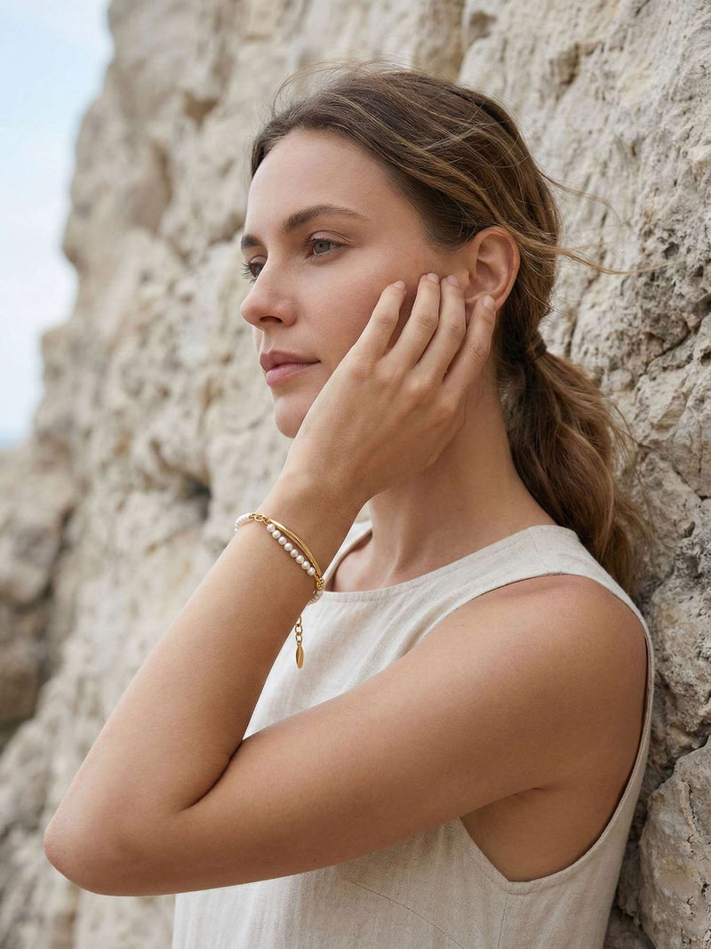 Seitenprofil Model berührt Gesicht trägt Perlenarmband Elva goldener Blattanhänger sichtbar