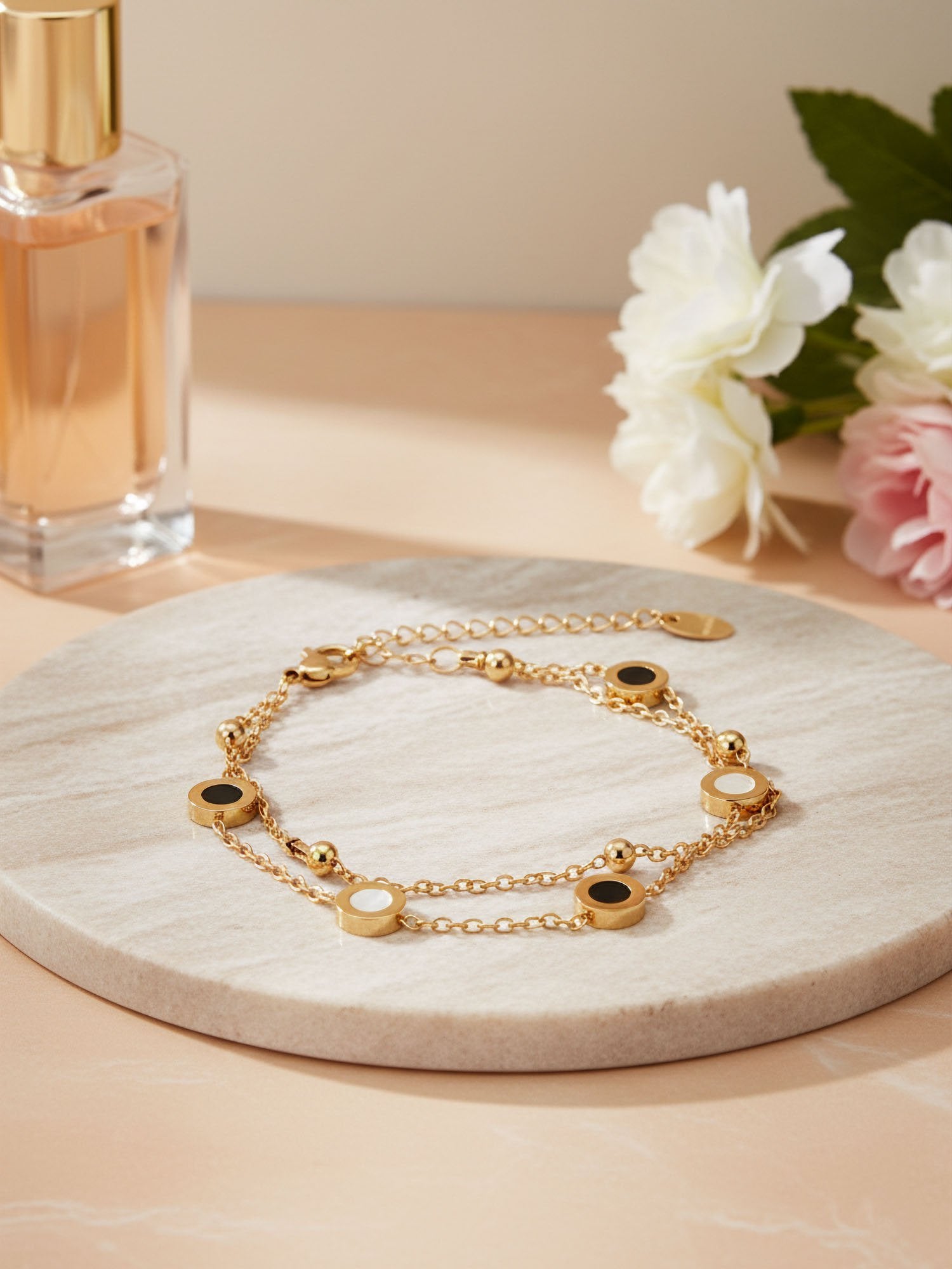 Luna Dual Armband Flatlay mit Blumen - Goldenes Doppelarmband mit Emaille-Details auf Marmor mit Pfingstrosen dekoriert