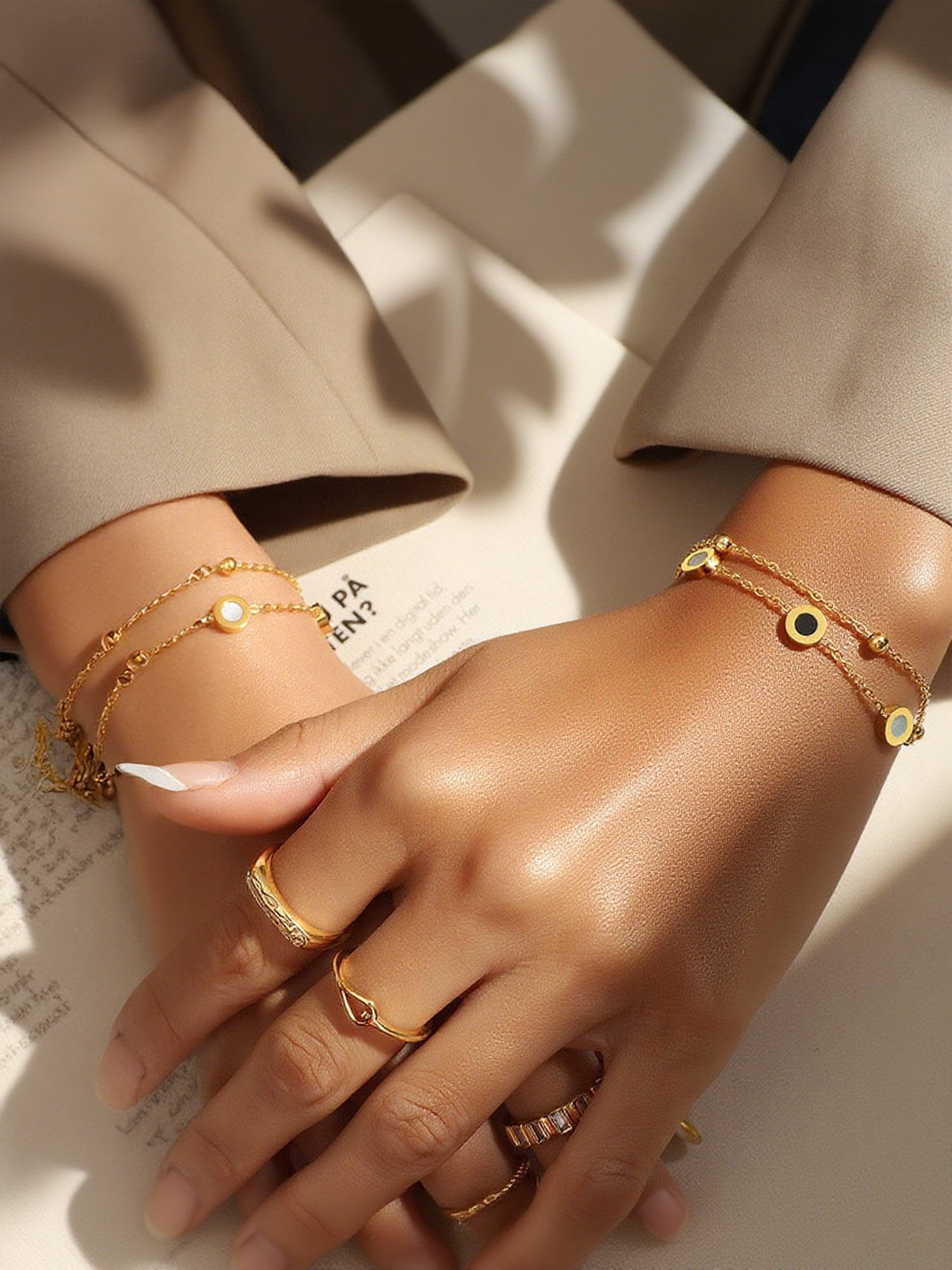 Zwei Luna Dual Armbänder an beiden Handgelenken getragen - Vergoldete Armbänder mit Yin-Yang-Kreisen in Schwarz-Weiß an Frauenhänden