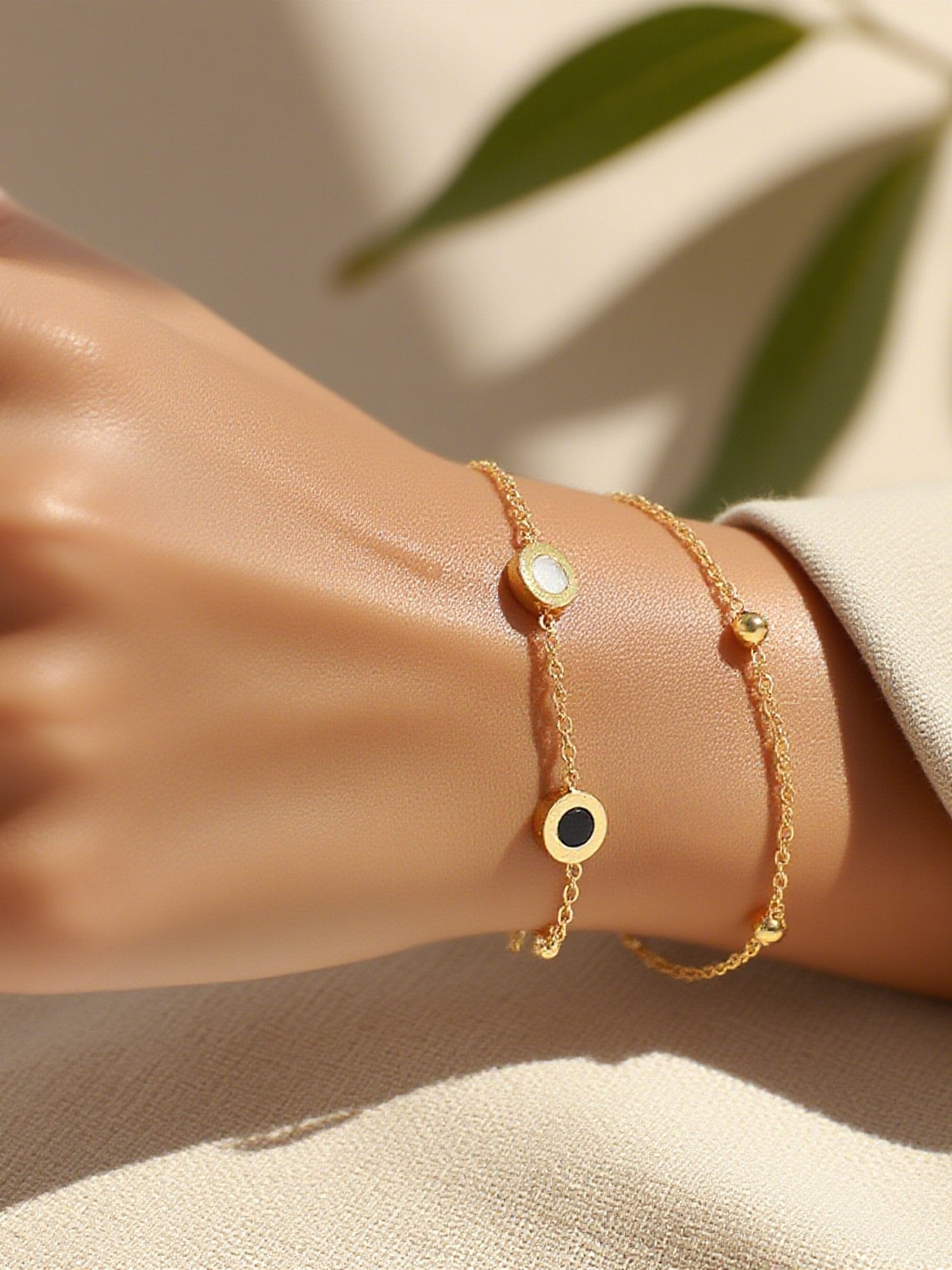 Luna Dual Goldarmband am Handgelenk - Doppelketten-Armband mit schwarzen und weißen Emaille-Details elegant getragen