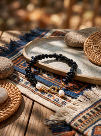 Armband Midnight Pearl mit schwarzen und weißen Akzenten auf einem gemusterten Tischläufer