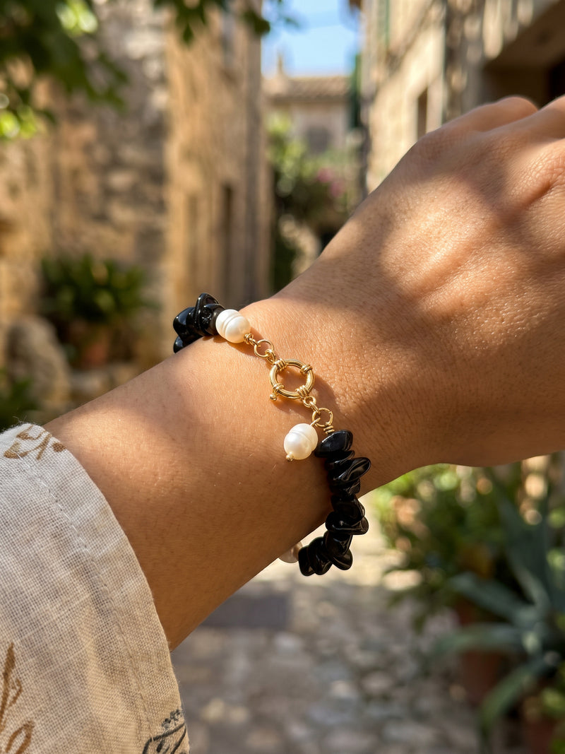 Nahaufnahme des goldfarbenen Ringverschlusses und der weißen Akzente am Armband Midnight Pearl