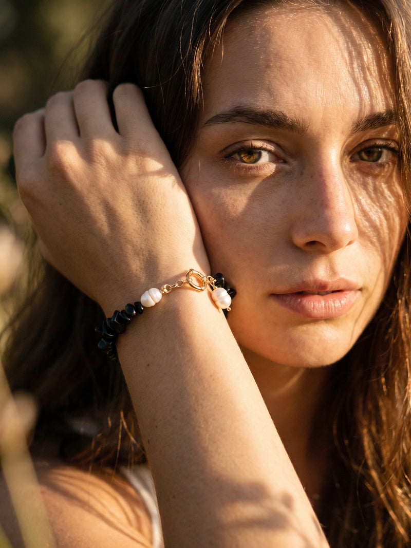 Armband Midnight Pearl am angehobenen Handgelenk, Detailaufnahme neben dem Gesicht