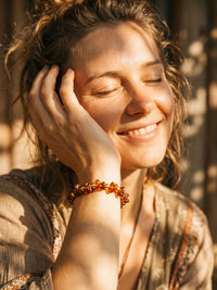 Armband Vulkanblüte am Handgelenk eines lächelnden Models im warmen Licht