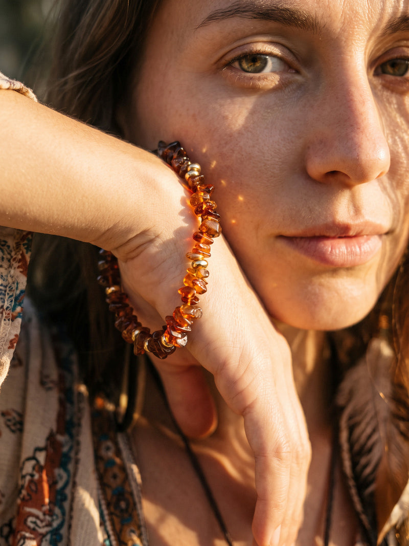 Armband Vulkanblüte am angehobenen Handgelenk neben dem Gesicht eines Models