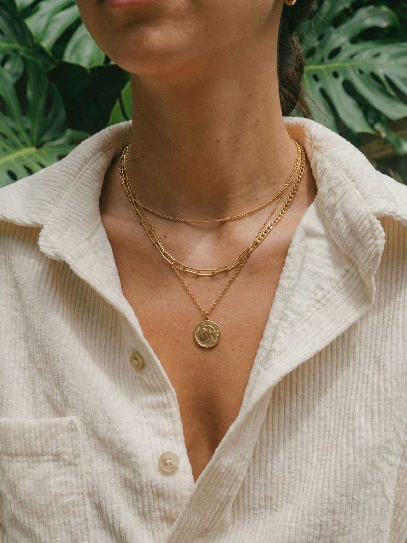 Aurelia Muenze Kette Lifestyle Foto goldene dreireihige Halskette mit Muenzanhaenger im warmen Sonnenlicht