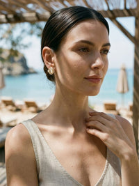 Celestia Ohrringe Sommer-Lifestyle – Model im Leinen-Top mit Katzenauge-Ohrsteckern, Strandbar-Atmosphaere am Meer