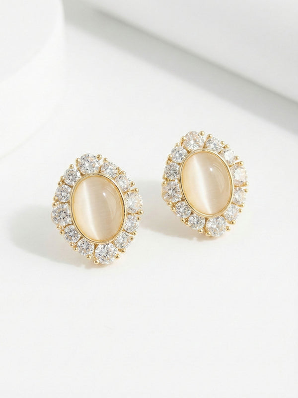 Celestia Katzenauge Ohrringe Produktfoto – vergoldete Ohrstecker mit ovalem Katzenauge-Stein und funkelnden Zirkonia-Kristallen auf weissem Hintergrund