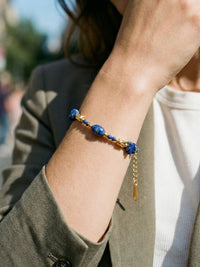 Deep Sea Armband am Handgelenk getragen – tiefblaue Lapislazuli-Perlen und goldene Metallperlen im natuerlichen Licht