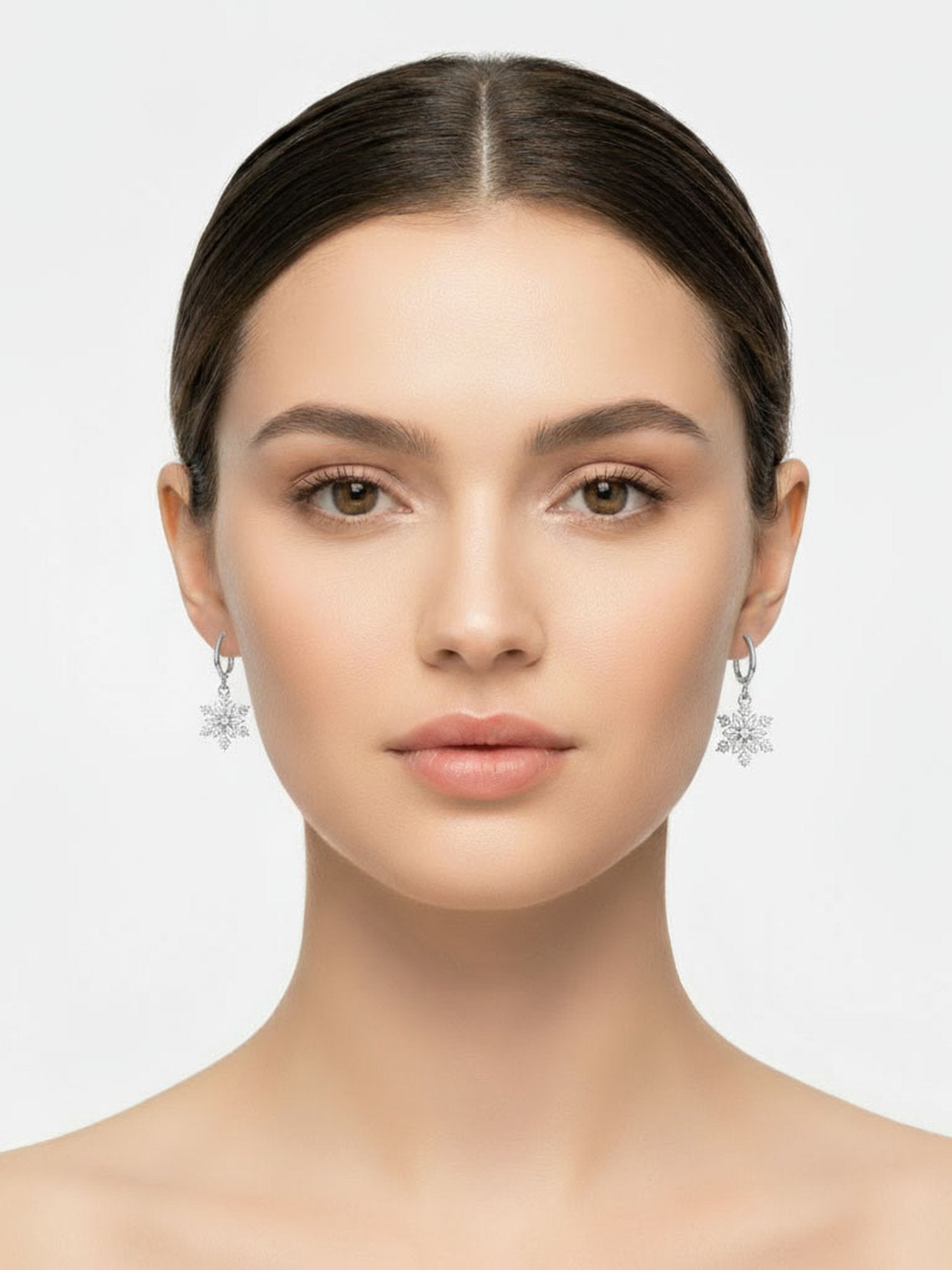 DREHBARE Schneeflocken-Ohrringe Trageansicht – Frau trägt silberne Schneeflocken-Creolen frontal Weihnachts-Lifestyle-Fotografie