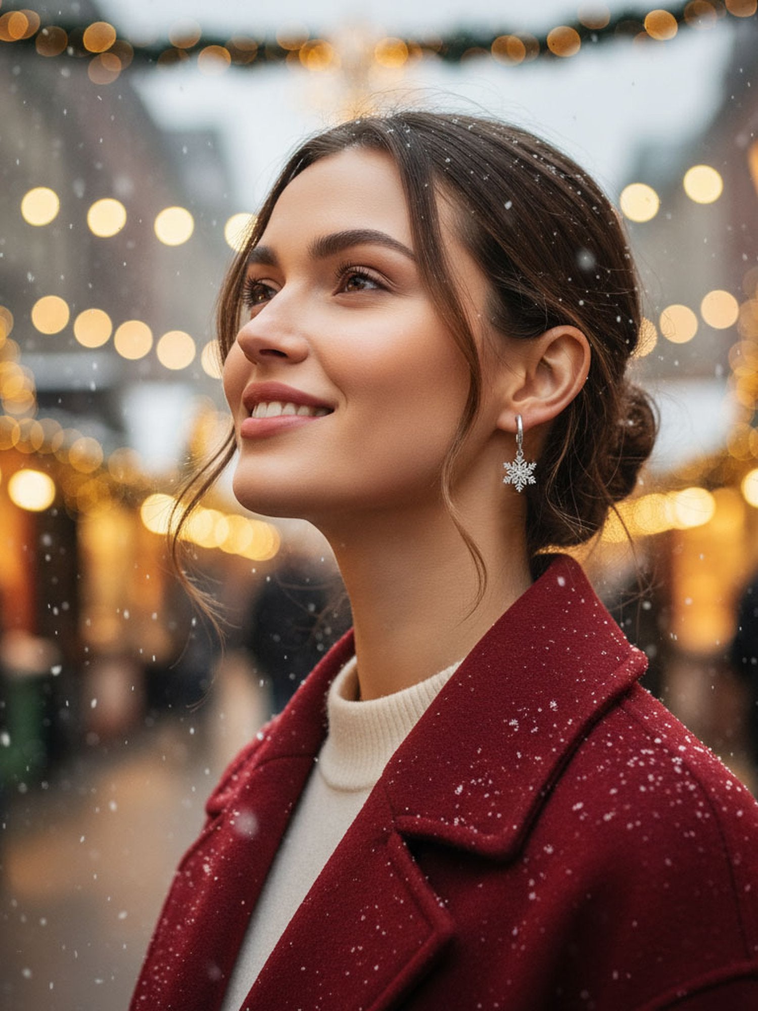 DREHBARE Schneeflocken-Ohrringe auf Weihnachtsmarkt – Frau trägt silberne Schneeflocken-Ohrringe mit rotem Mantel im Schnee bei Weihnachtsbeleuchtung
