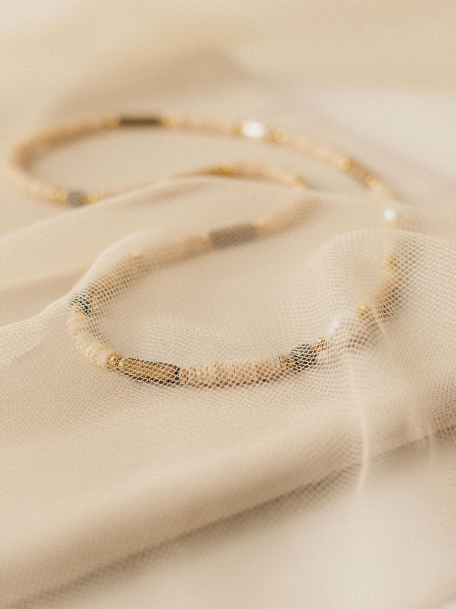 Earthlines Kette auf Stoff drapiert - Boho-Perlenkette mit Heishi-Steinen in Erdtönen und Perlendetails Flatlay-Ansicht