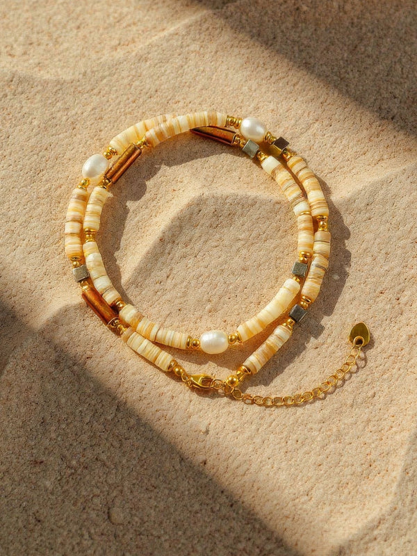 Earthlines Halskette auf Sand - Boho-Perlenkette mit Heishi-Steinen in Erdfarben natürlich inszeniert mit Trockenblumen