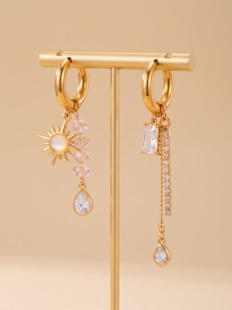 EH05C: Asymmetrische goldfarbene Creolen mit Sonne, rosa Perlen und klaren Tropfen am Schmuckständer.
