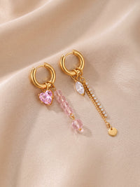 EH05D: Asymmetrische goldfarbene Creolen mit rosa Herz, rosa Perlen und feiner Kette auf hellem Stoff.