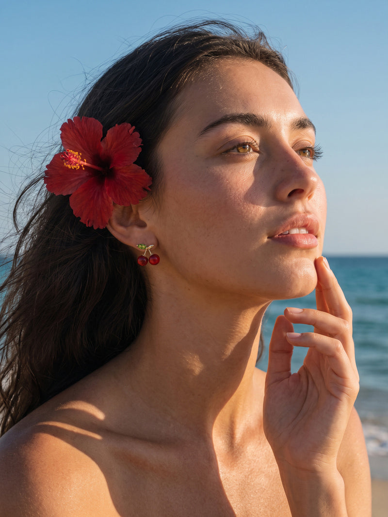 EH56: Kirsch-Ohrstecker im Porträt am Meer mit roter Blüte im Haar getragen.