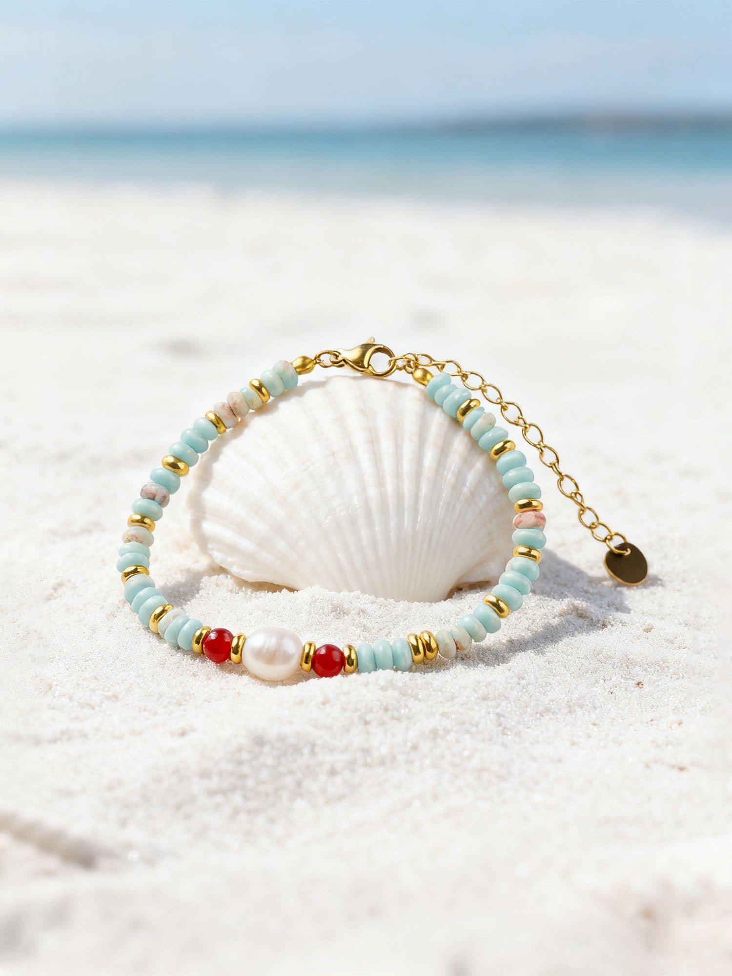 Natursteinarmband mit Shoushan-Stein und Perle auf weißer Muschel am Strand – detailreiche Produktfotografie mit maritimem Ambiente