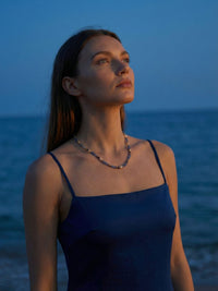 Sodalith Perlenkette Ocean Night kuenstlerisches Portrait - Model blickt zum Himmel am Meer bei Daemmerung