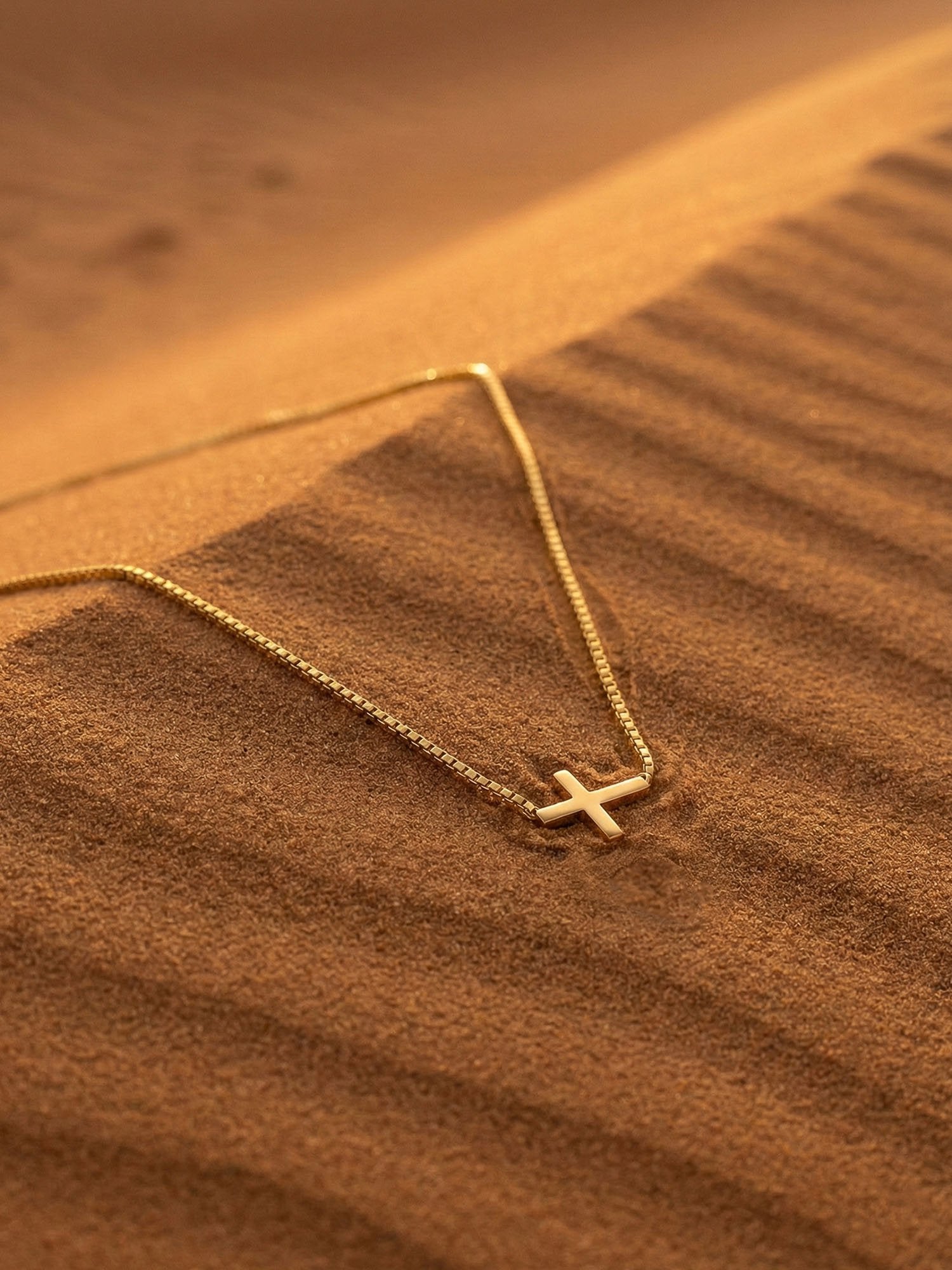 Der Horizont Kreuz-Kette Flatlay Leder – 18K vergoldete Halskette auf braunem Wildleder mit warmem Lichtspiel