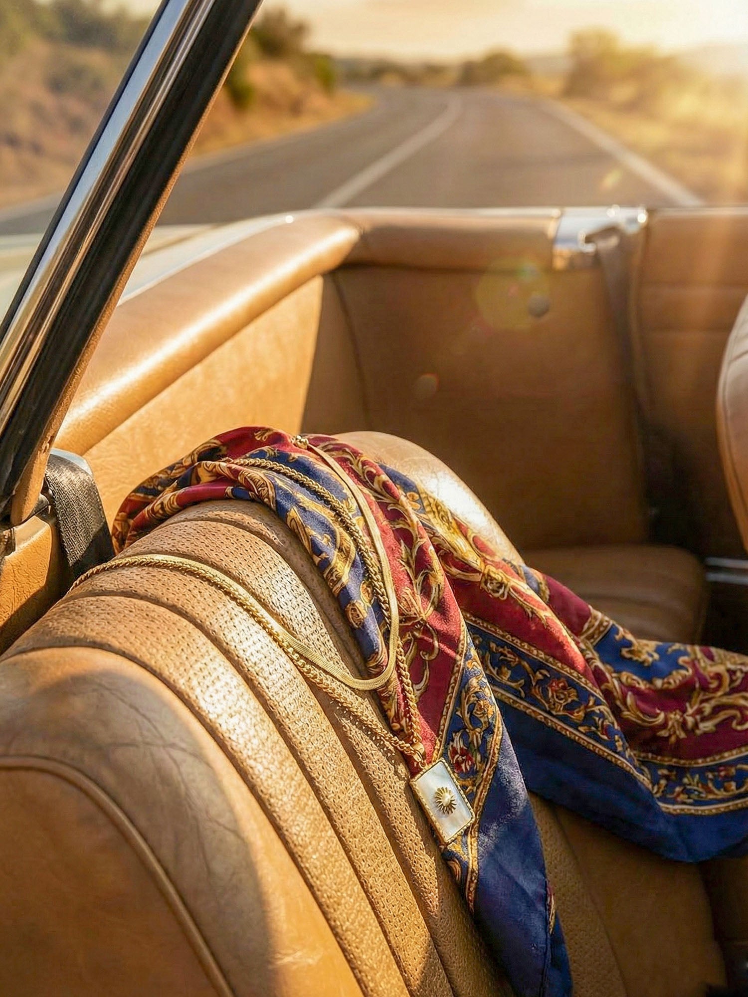 Kette Lichtträgerin Flatlay im Cabrio – goldene Doppelkette mit Perlmutt auf Ledersitz mit Seidentuch