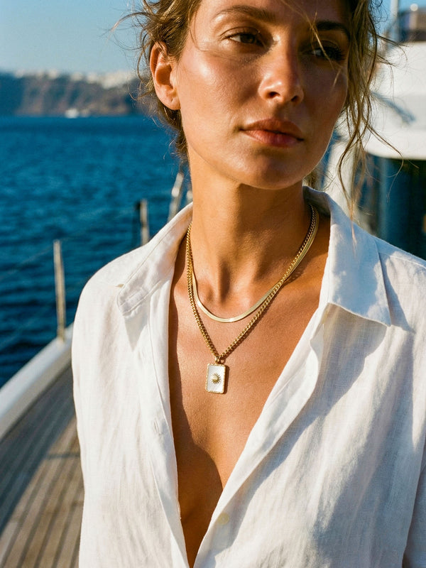 Lichtträgerin Halskette California Style – Frau mit Jeansjacke trägt goldene Sonnen-Kette am Strand