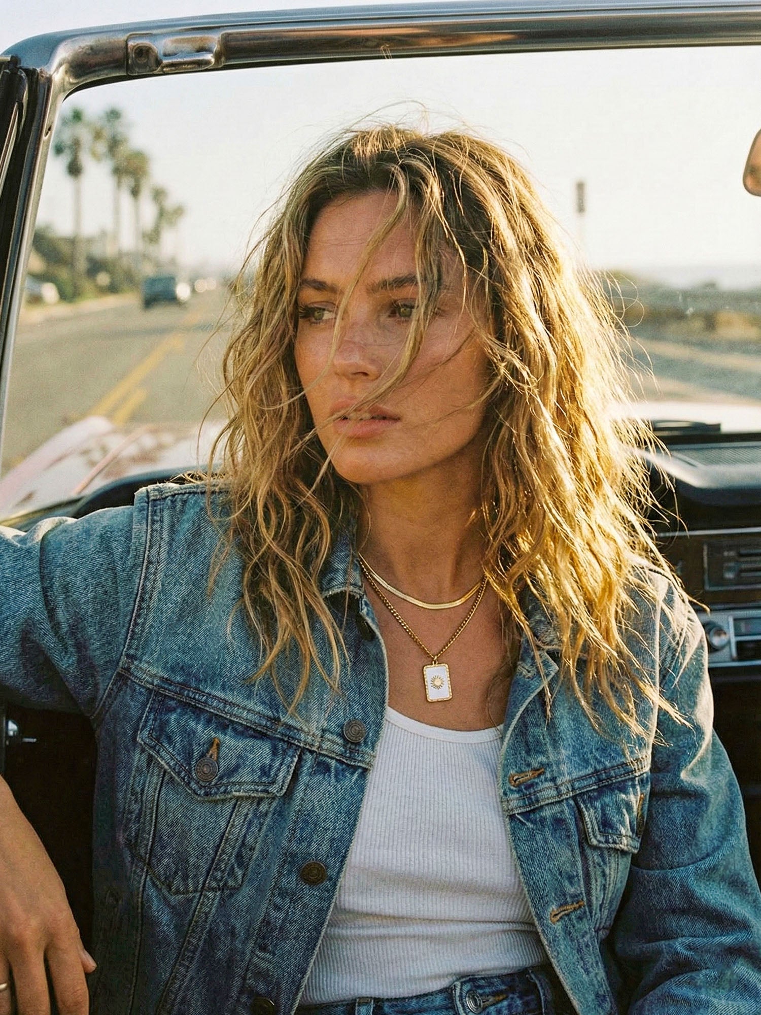 Lichtträgerin Goldkette Roadtrip Lifestyle – Frau trägt Doppelkette mit Sonnenanhänger im Cabrio
